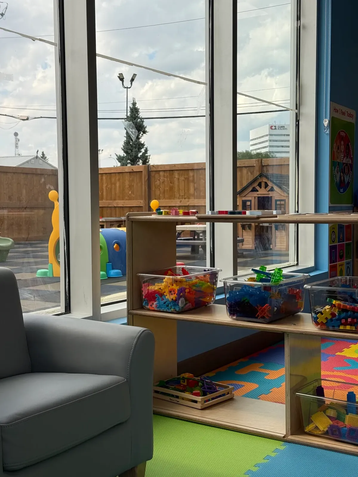 View of the fenced outdoor play yard with a playhouse and tunnel